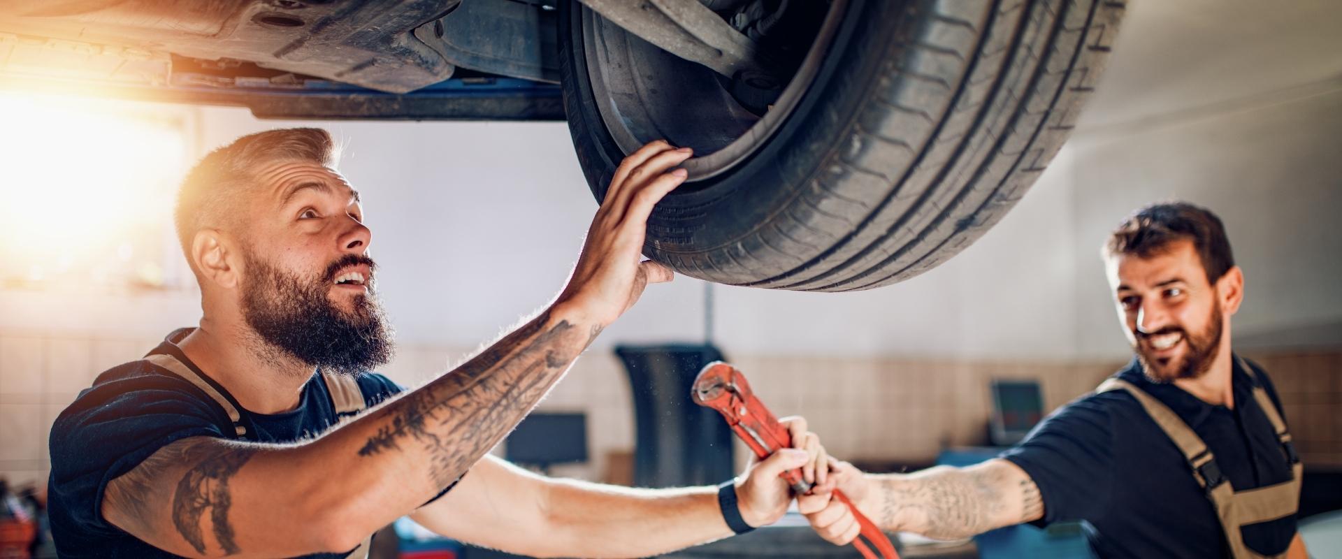 Mecânico de Auto Center preocupado olhando carro parado em elevador de oficina devido a falta de peças automotivas